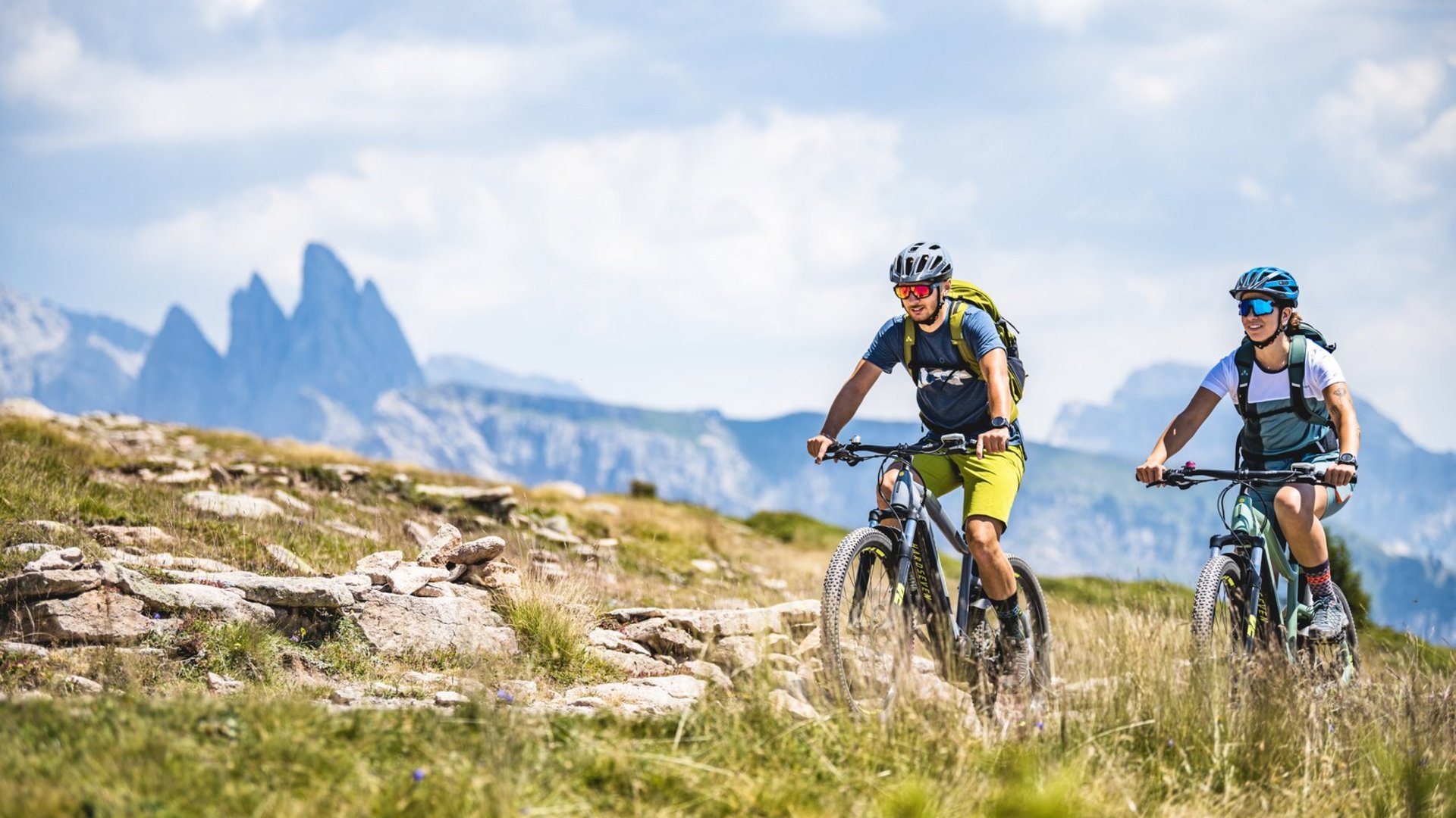 Syklister på sti i Val Gardena med fjellene i bakgrunnen