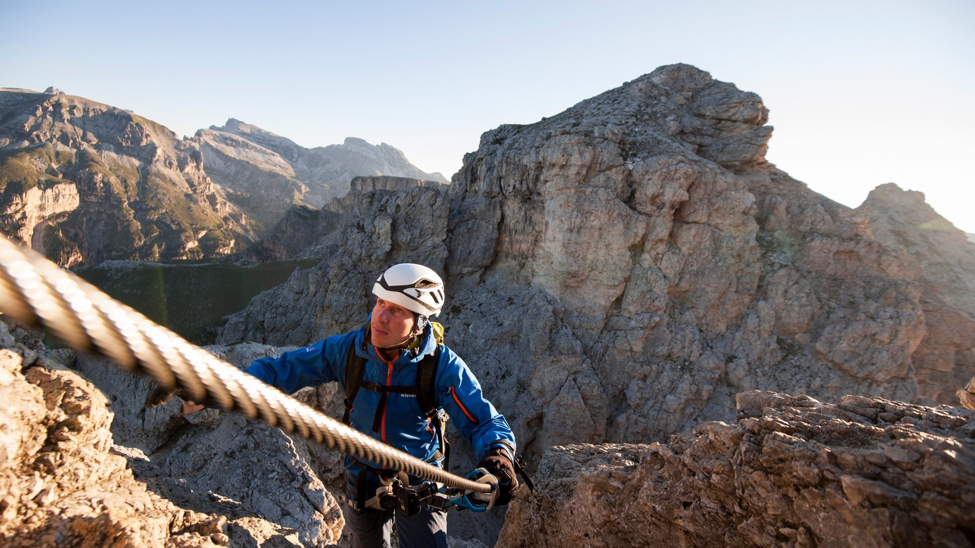 Klatrere med hjelm og sele i via ferrata på loddrett fjellvegg