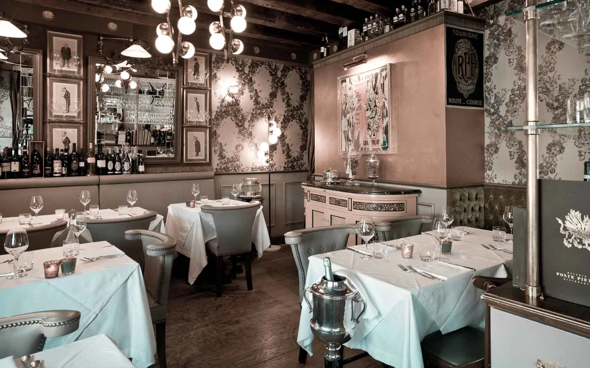 Restaurantbord ved elven med utsikt mot Ponte Pietra i solnedgang